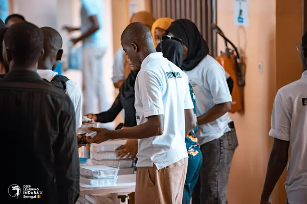 Des bénévoles en polos blancs distribuent les repas aux participants dans le hall